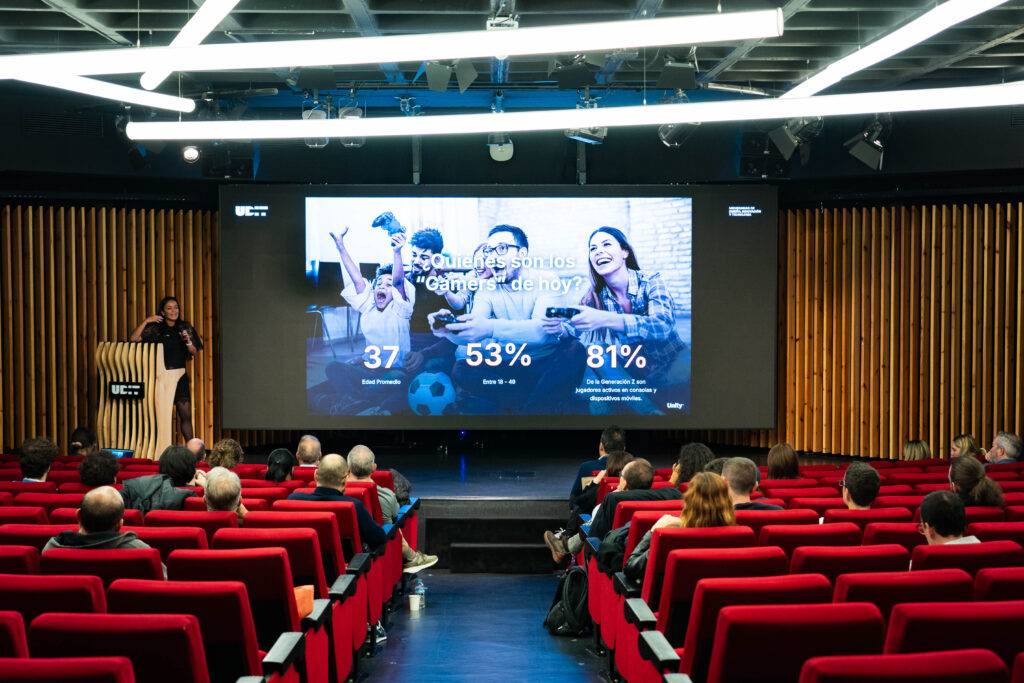 Una conferencia sobre la importancia del deporte en la actualidad, con un presentador y una gran pantalla que muestra estadísticas.