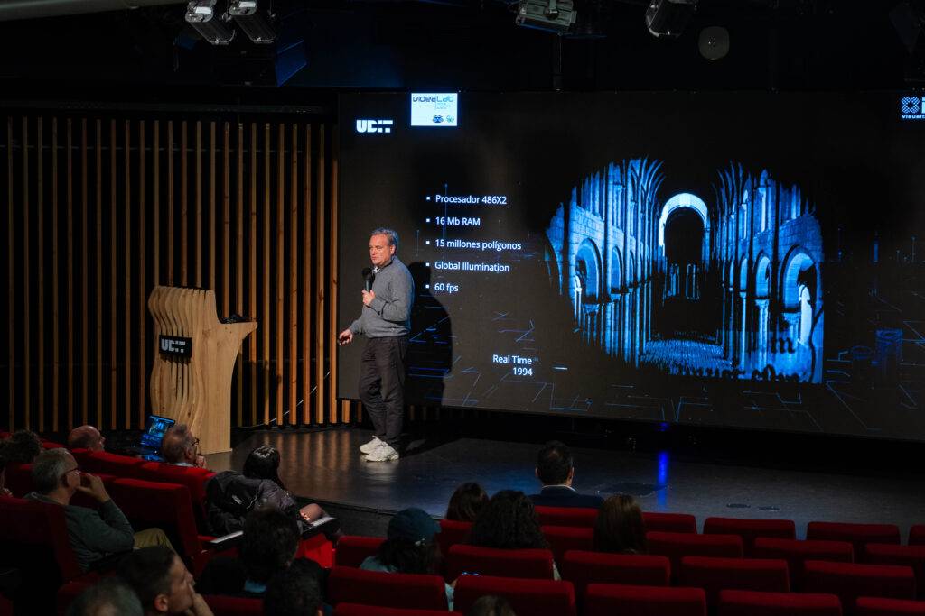 Un presentador habla sobre tecnología en una conferencia con un proyector detrás mostrando información técnica.