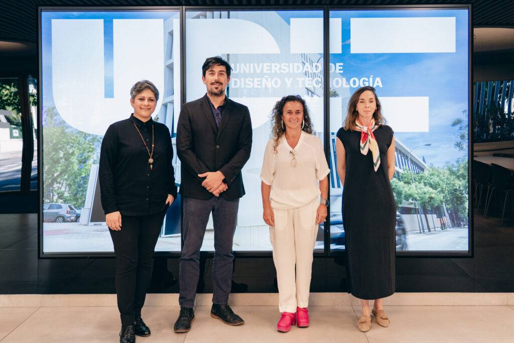Cuatro personas posan frente a una pantalla con el logo de la Universidad de Diseño y Tecnología.