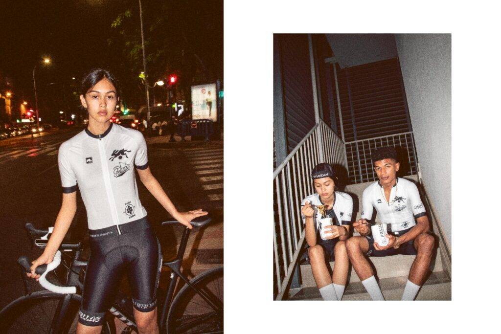 Una ciclista posando con su bicicleta, junto a dos jóvenes sentados en unas escaleras disfrutando de comida.