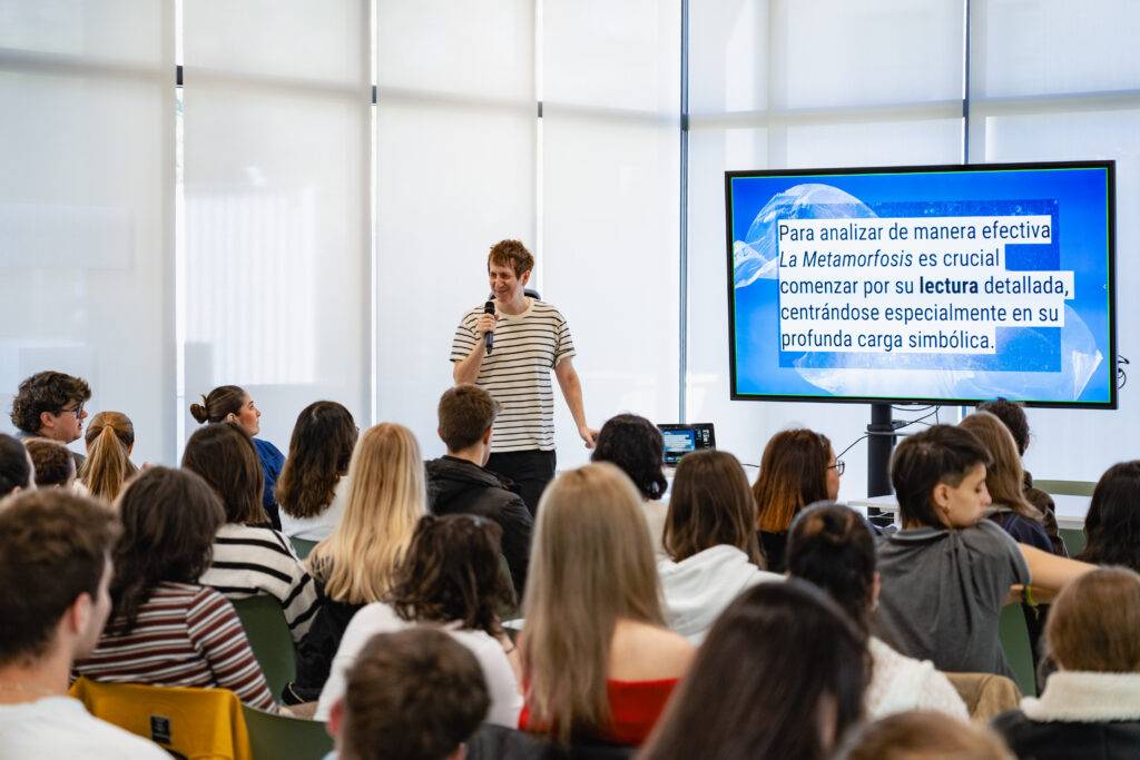 Un grupo de estudiantes escucha atentamente a un presentador que está ofreciendo una charla sobre la Metamorfosis.