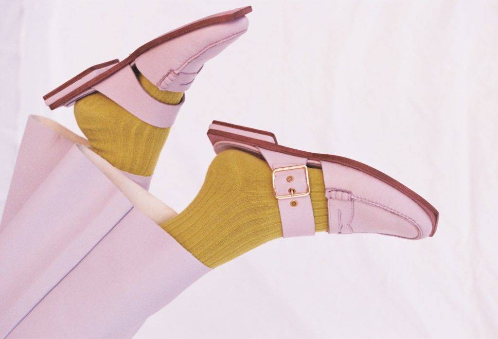 Un par de zapatos de mujer de color rosa claro con calcetas y calcetines amarillos brillantes.