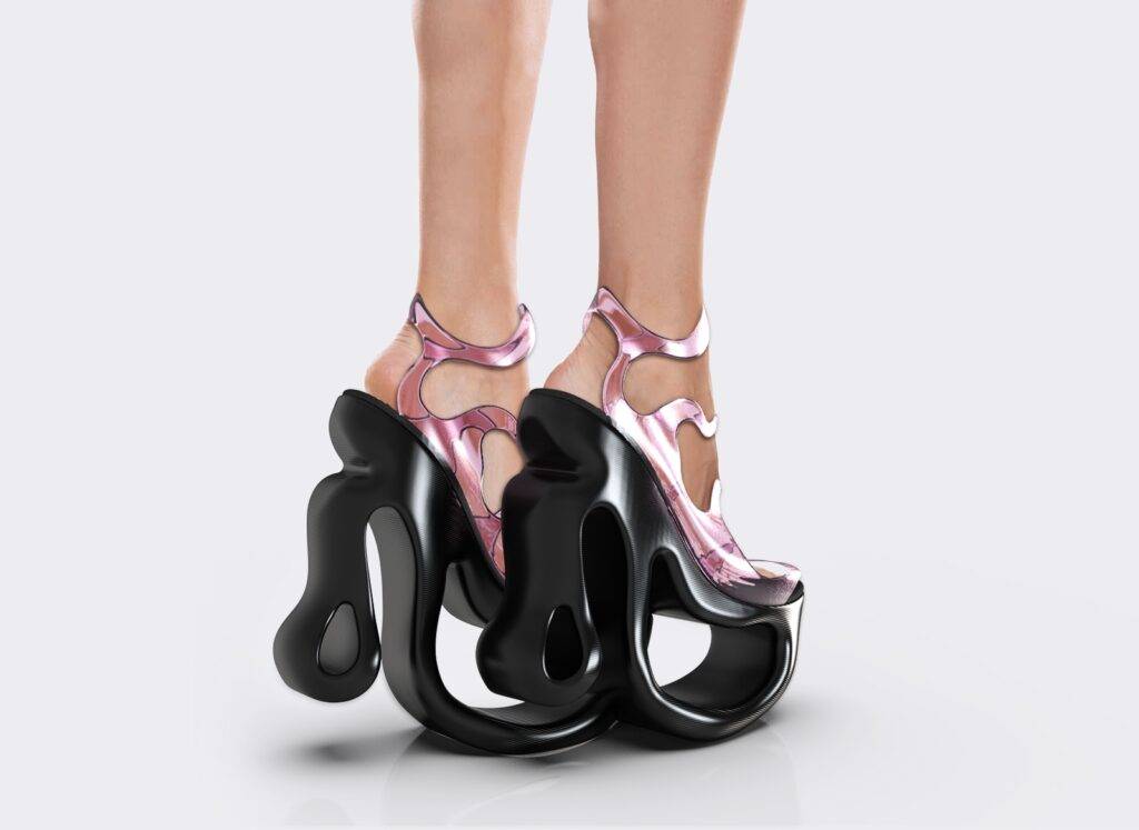 Un par de zapatos de tacón alto con un diseño moderno y abstracto en tonos rosa y negro.