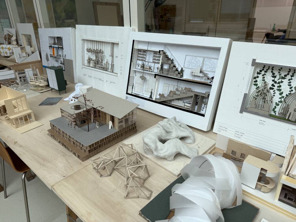 Una mesa con diferentes maquetas arquitectónicas y planos expuestos.