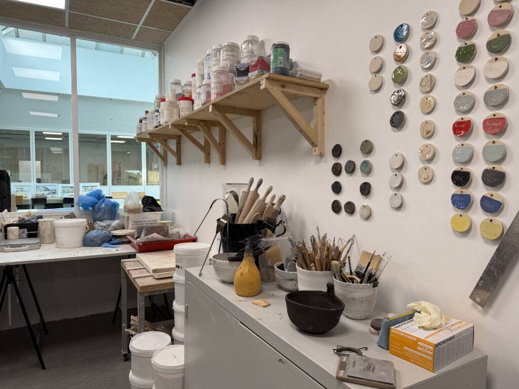 Una habitación de trabajo artística con estanterías llenas de materiales y utensilios.