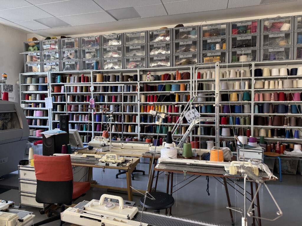 Una sala de trabajo con estanterías llenas de hilos de colores y máquinas de coser.