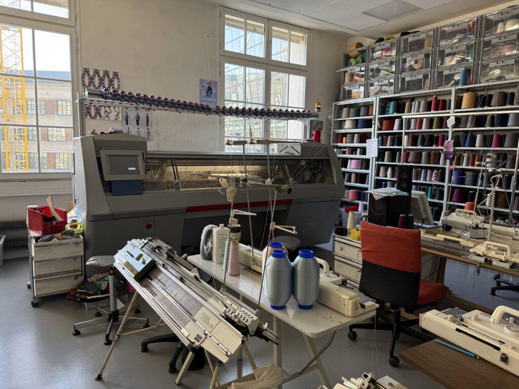 Un taller de confección textil con máquinas de tejer y estantes llenos de hilos de colores.