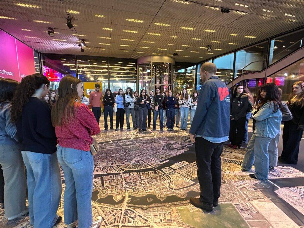 Un grupo de personas se encuentra reunido en un espacio interior, observando un gran mapa en el suelo.