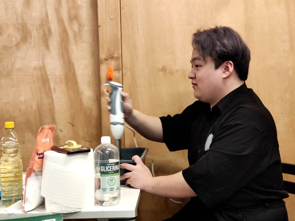 Una persona utiliza un batidor manual en una mesa llena de ingredientes para cocinar.