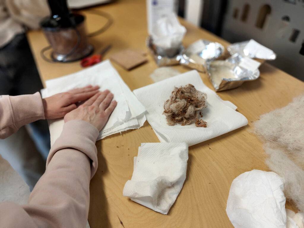 Unas manos trabajando en una mesa con diferentes materiales y utensilios para manualidades.
