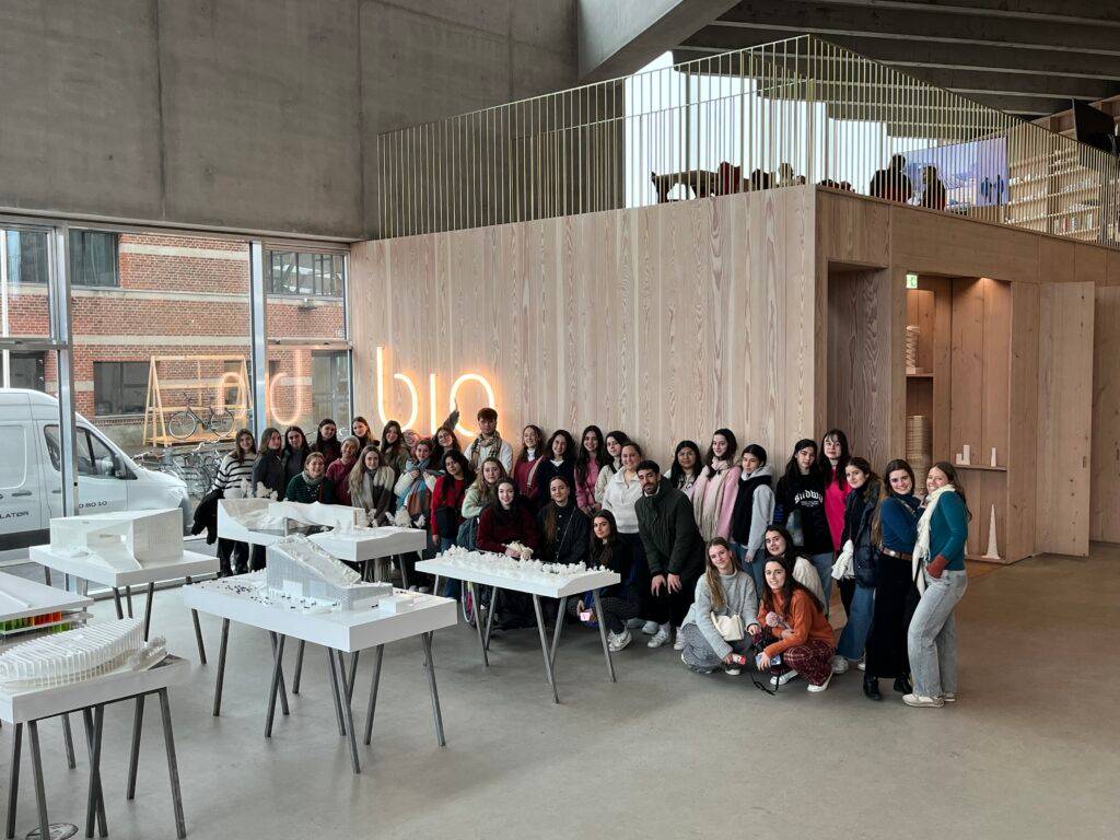 Un grupo grande de personas posando en un espacio interior moderno con modelos arquitectónicos en mesas.