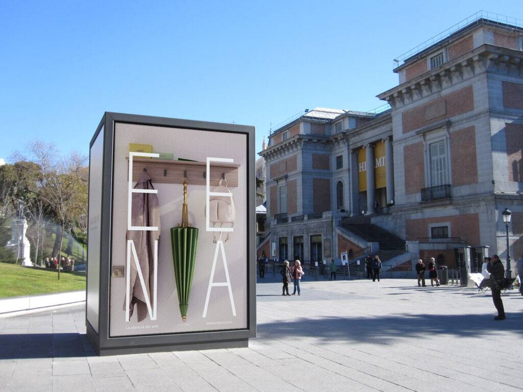 Una estructura moderna con paraguas de colores se encuentra en una plaza frente a un museo.
