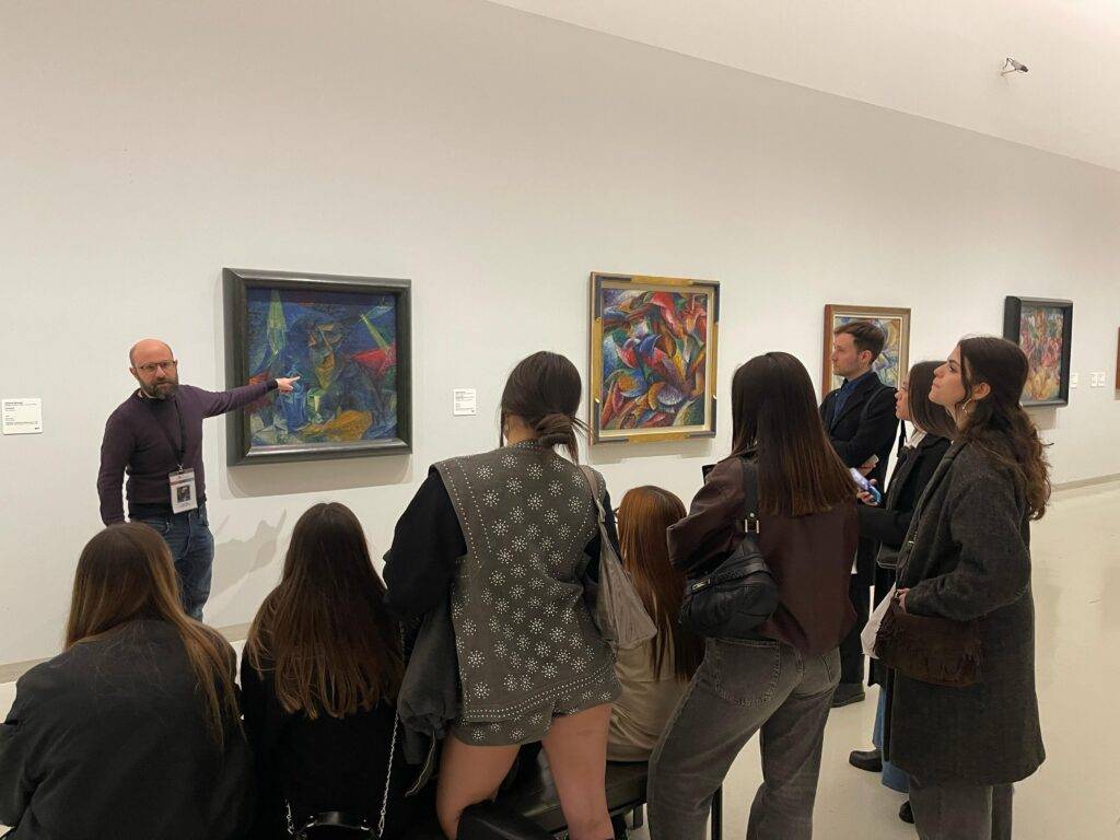 Un grupo de personas escucha atentamente a un guía que explica obras de arte en una galería.