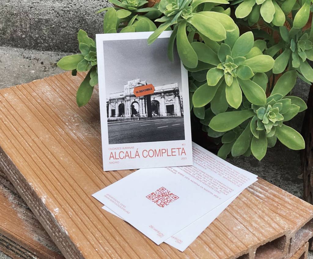 Una tarjeta en blanco y negro que muestra un edificio emblemático, acompañada de folletos sobre Alcalá.