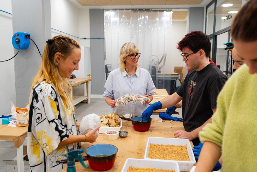Un grupo de personas está trabajando en un taller de manualidades en una mesa, utilizando diferentes materiales.