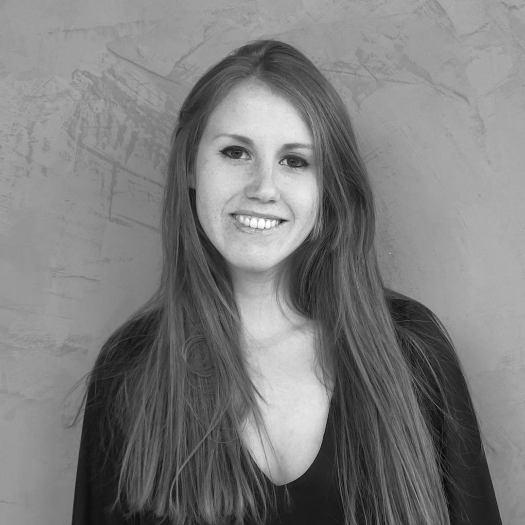 Una mujer sonriente con cabello largo en una fotografía en blanco y negro.