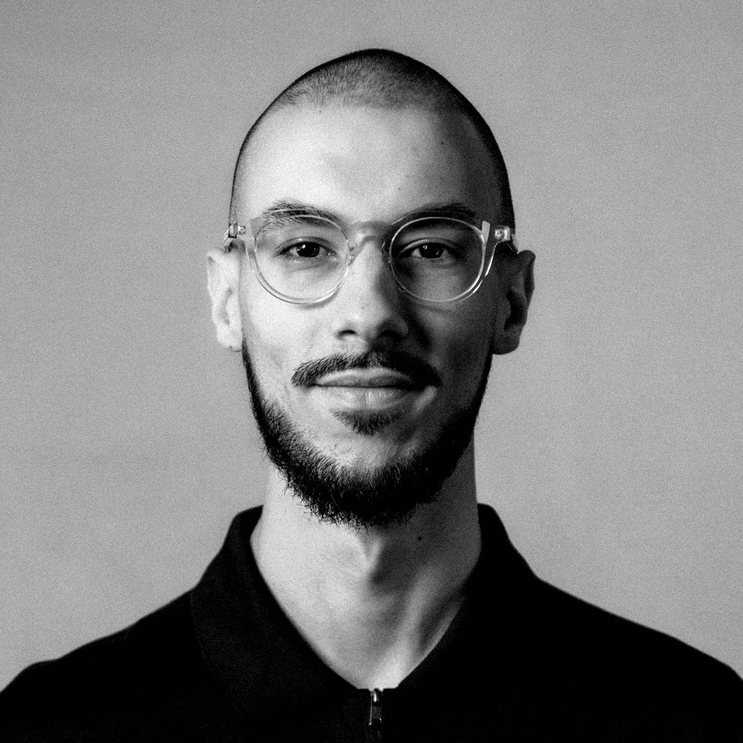 Retrato en blanco y negro de un hombre con gafas y barba, luciendo una expresión serena.