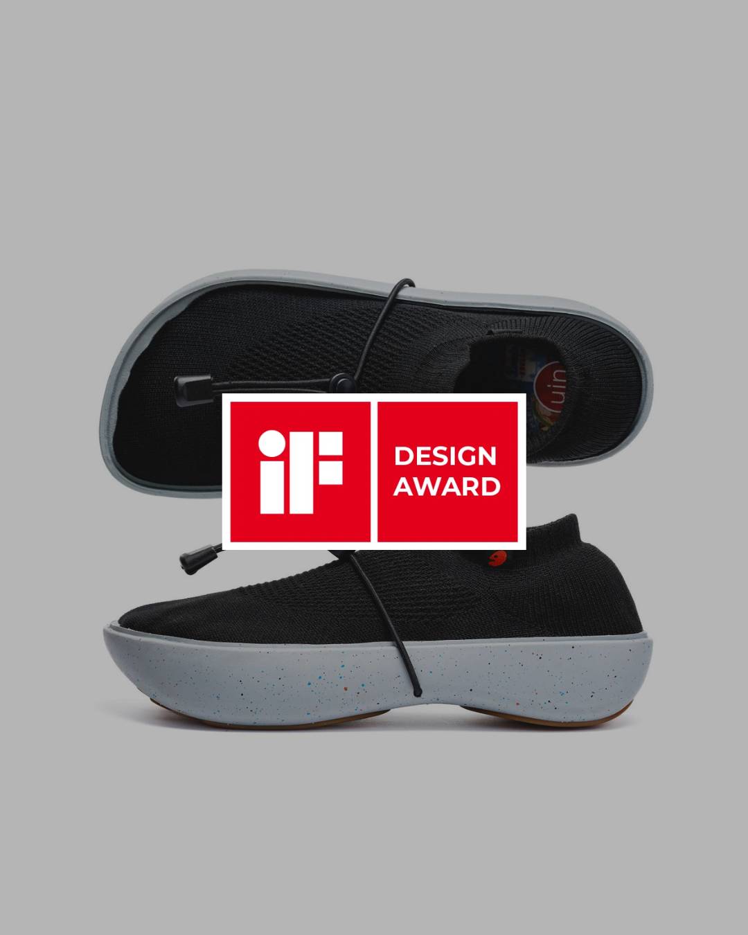 Un par de zapatillas de diseño moderno y minimalista con suela gris y parte superior negra.