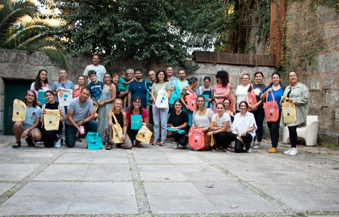 Un grupo de personas posando juntas al aire libre, sosteniendo bolsas de diferentes colores.