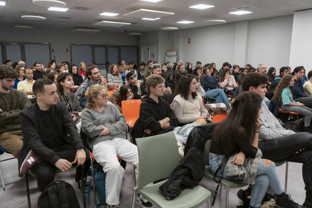 Una multitud de personas sentadas en una sala, prestando atención a un evento o conferencia.