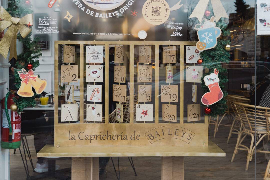 Una vitrina decorativa con un calendario de adviento de Baileys en la que se pueden ver varios compartimentos numerados y adornos navideños.