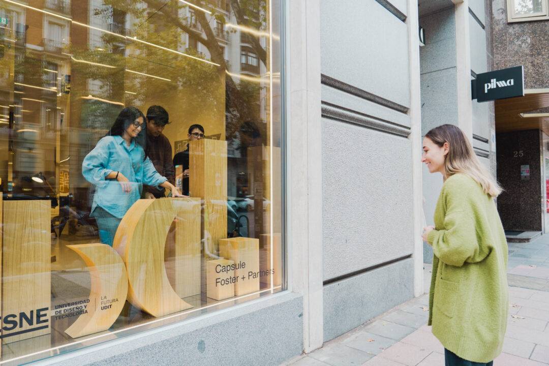 Una mujer observa a unas personas dentro de una tienda a través de un escaparate.