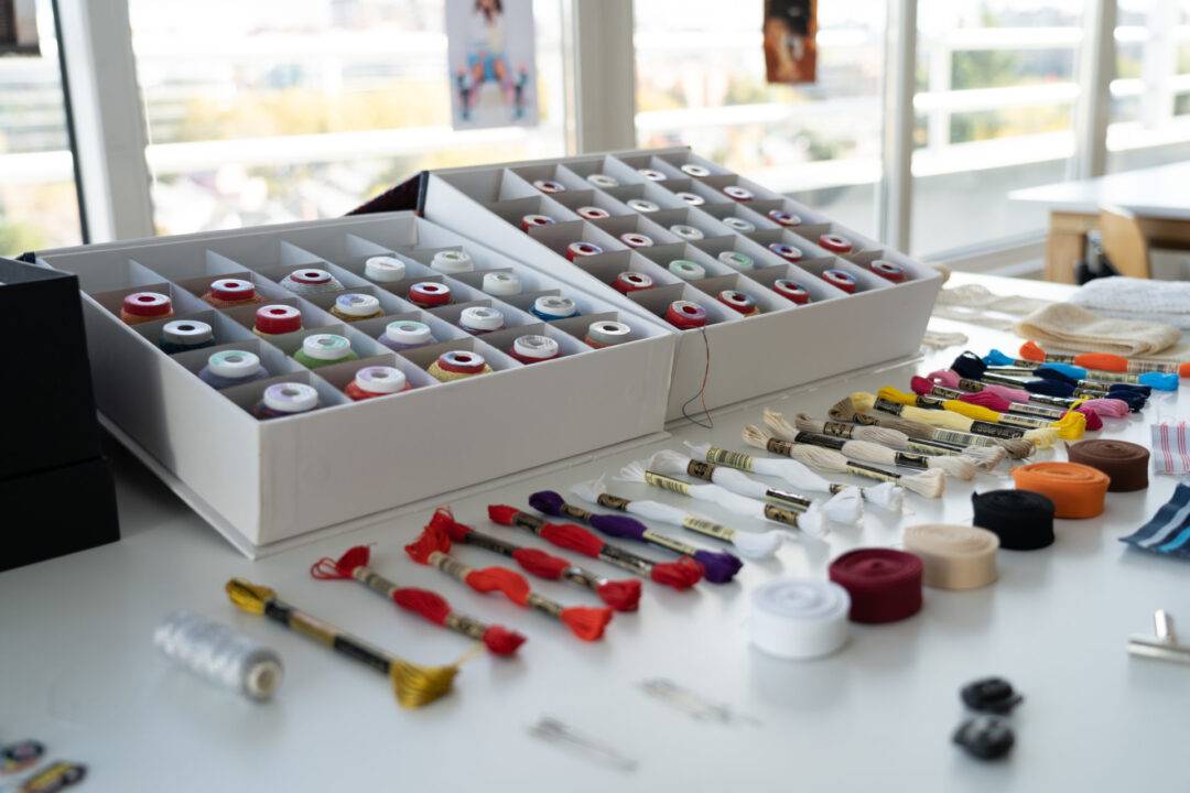 Un espacio de trabajo organizado con bobinas de hilo y herramientas de costura dispuestas sobre una mesa.