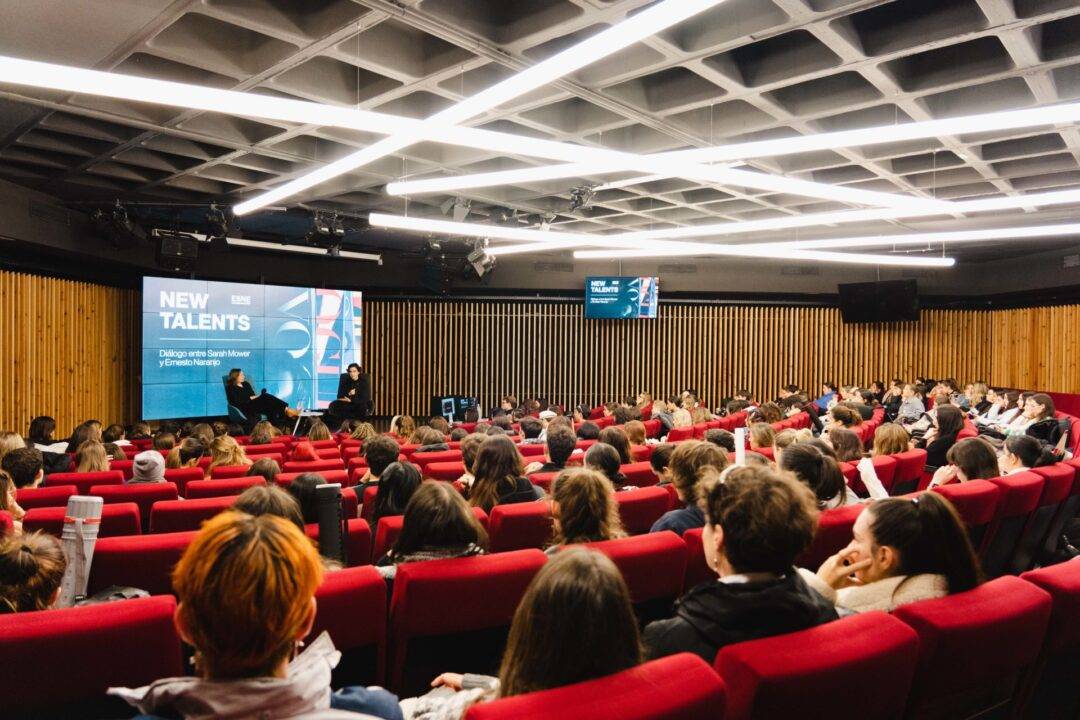 Un grupo numeroso de personas asiste a una charla sobre nuevos talentos en un auditorio moderno.