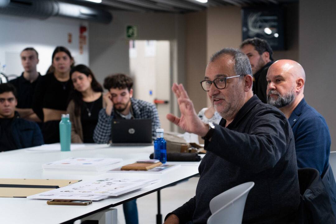 Un hombre habla con gestos durante una reunión con un grupo de personas en un entorno moderno.