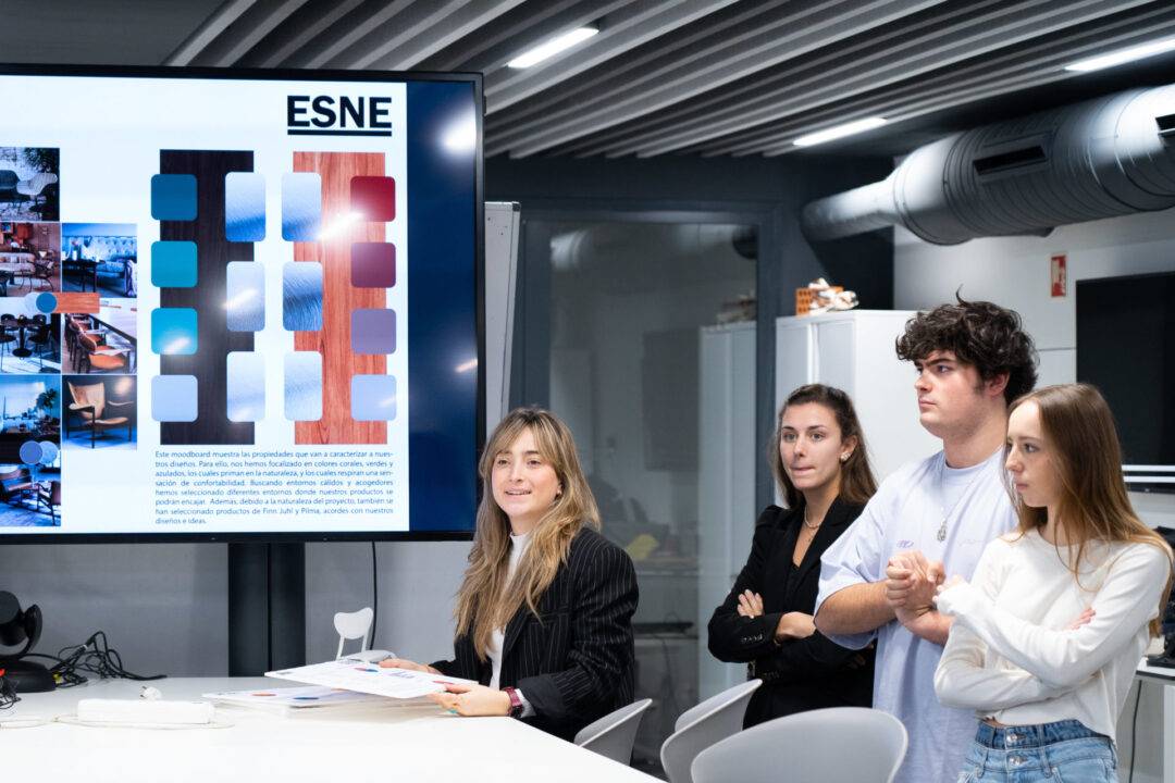 Un grupo de cuatro estudiantes en una sala de presentación, observando una pantalla con muestras de colores y fotografías.