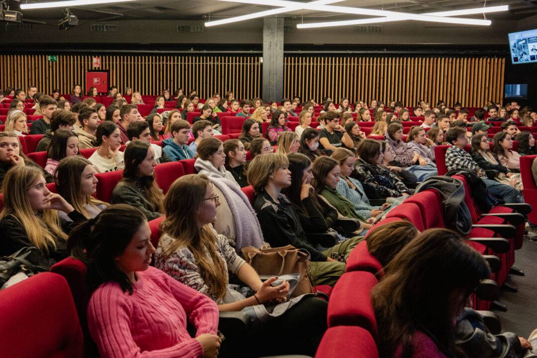 Un grupo numeroso de personas sentadas en un auditorio escuchando atentamente.