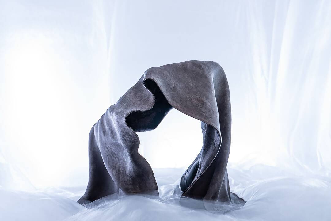 Una escultura abstracta que representa una forma envolvente de tejido oscuro.