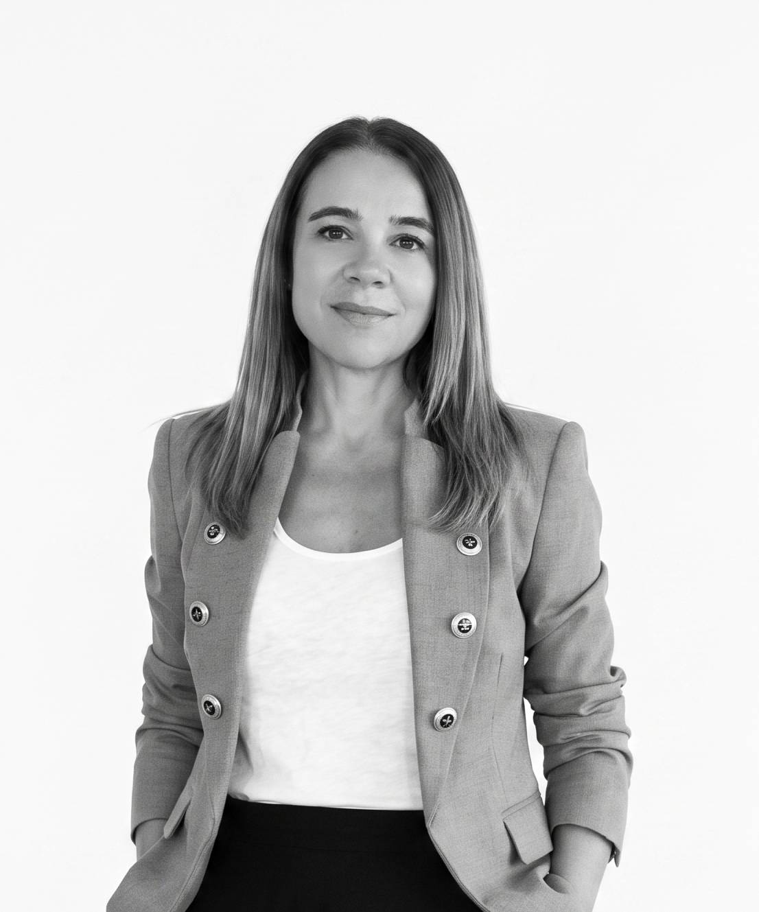 Una mujer con chaqueta de blazer posando con una expresión amigable.