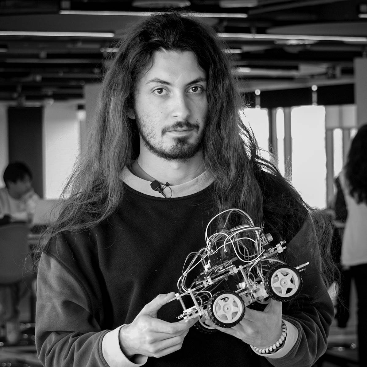 Una persona sostiene un robot en un entorno de aula.