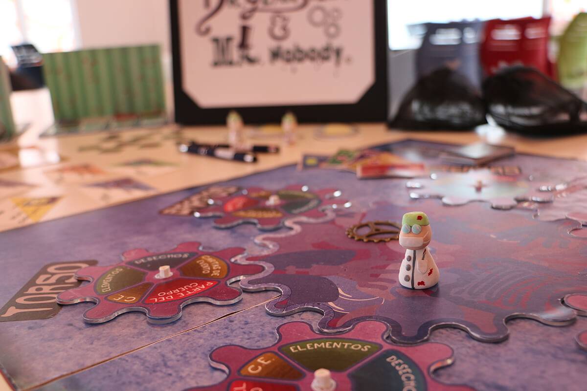 Una mesa con un juego de mesa que presenta piezas coloridas y un mini personaje destacado en el centro.