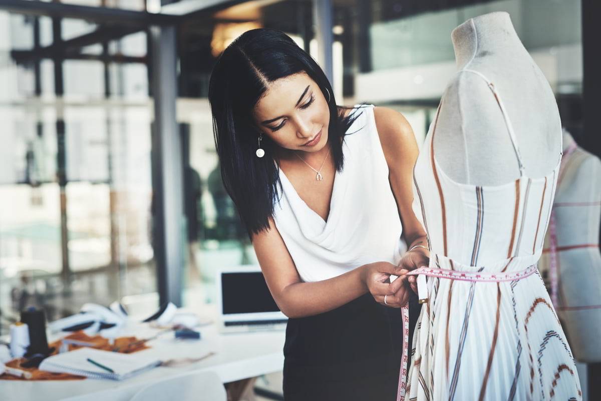 Una diseñadora ajusta una prenda en un maniquí en un entorno moderno de trabajo.