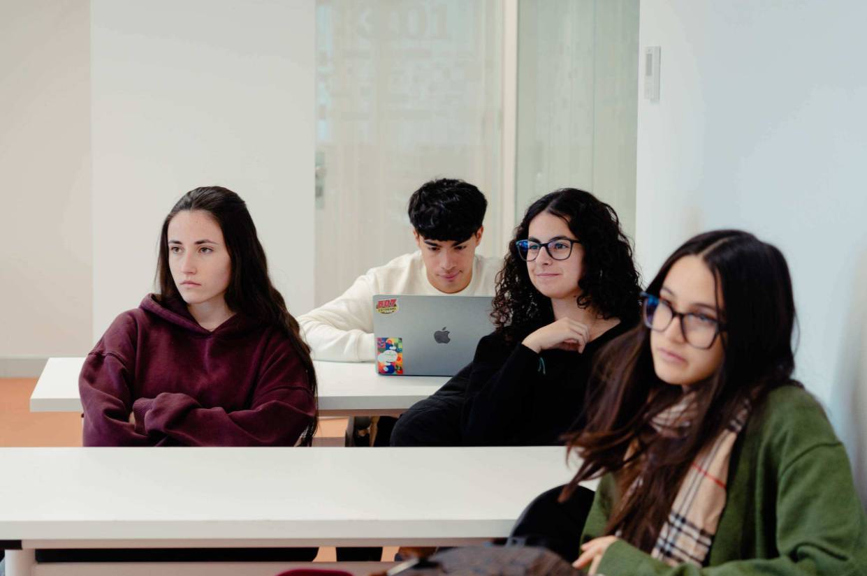 Un grupo de estudiantes sentados en un aula prestando atención.