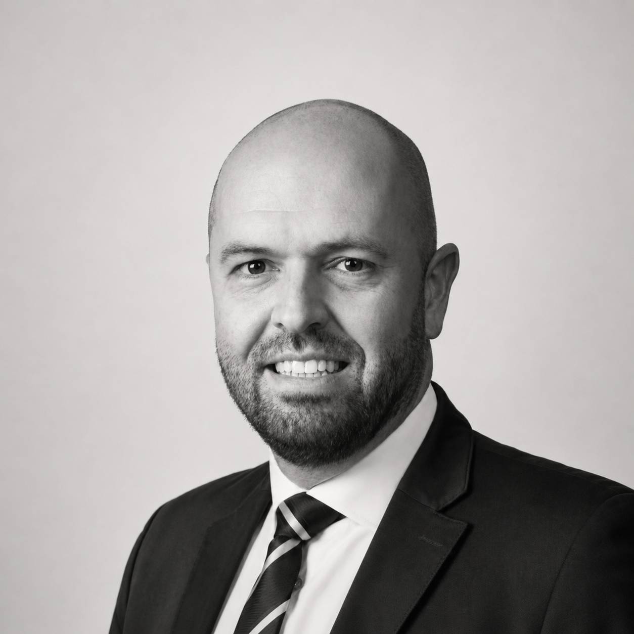 Retrato en blanco y negro de un hombre con barba y vestido formal.