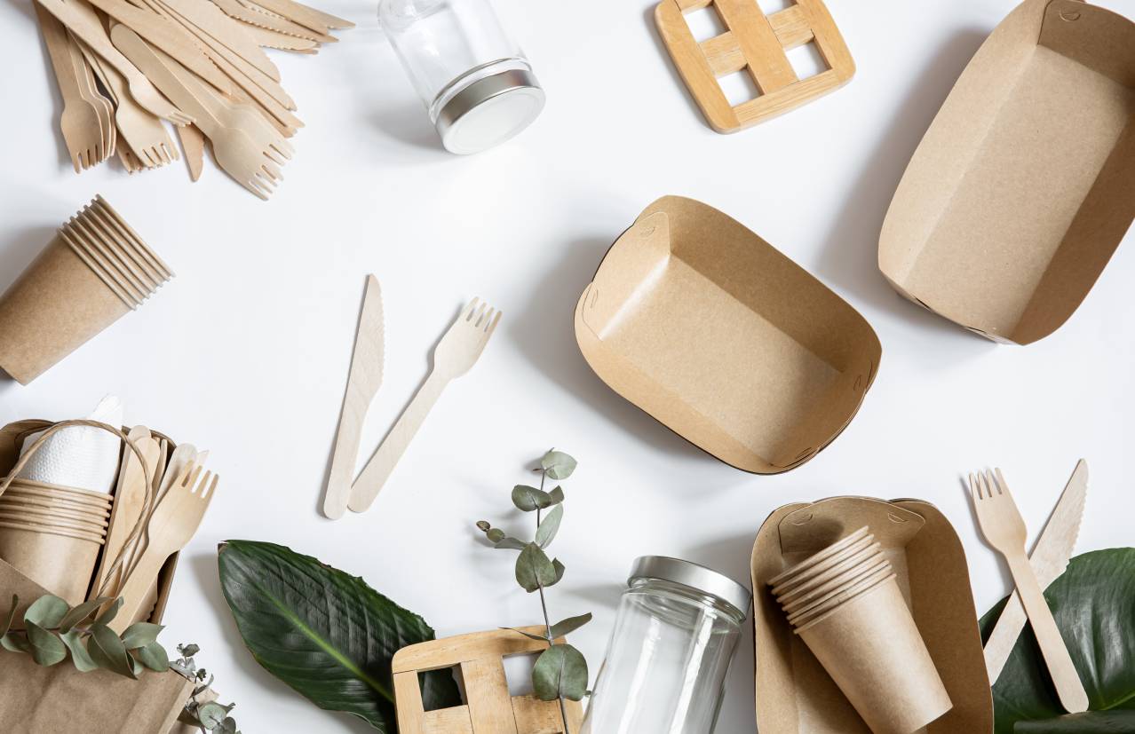 Una disposición de utensilios y envases de cartón sobre una superficie blanca.
