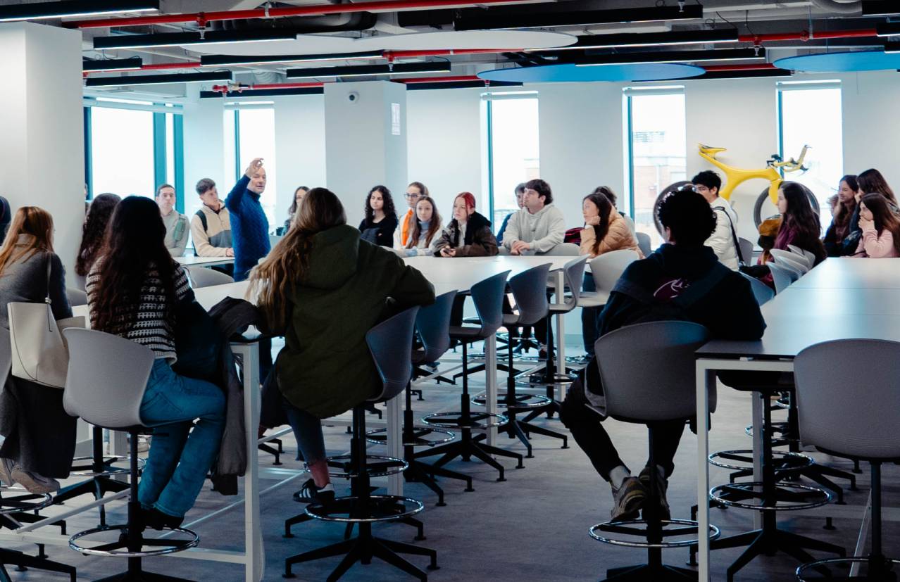 Un grupo de personas escucha a un orador en un ambiente moderno y luminoso.