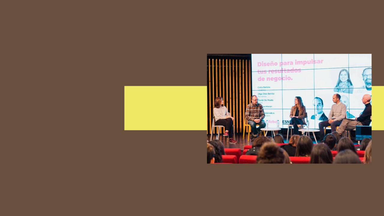 Una mesa redonda sobre diseño para impulsar negocios con varios ponentes en un escenario.