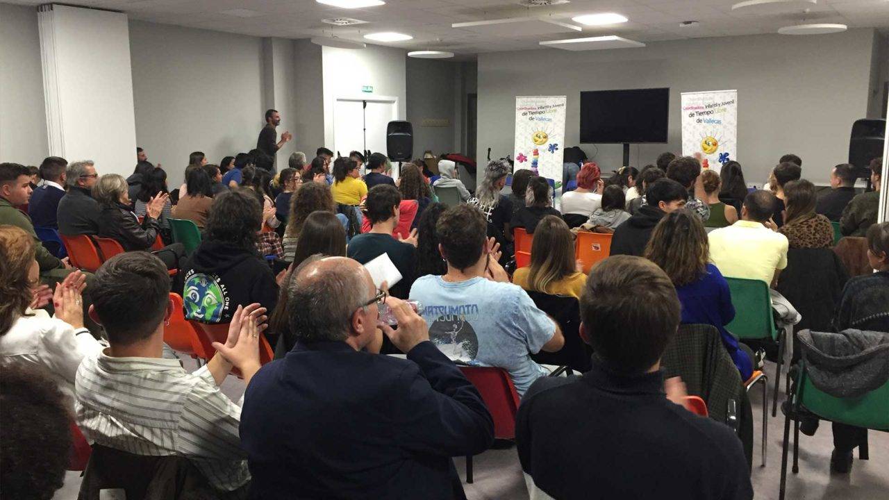 Una multitud aplaude durante un evento en un salón amplio.