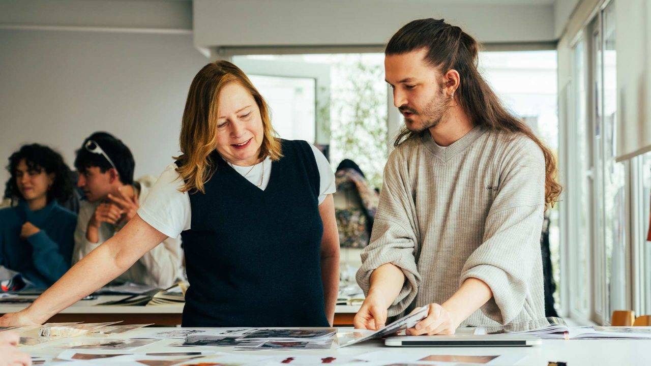 Dos personas revisan una colección de fotografías sobre una mesa en un entorno colaborativo.