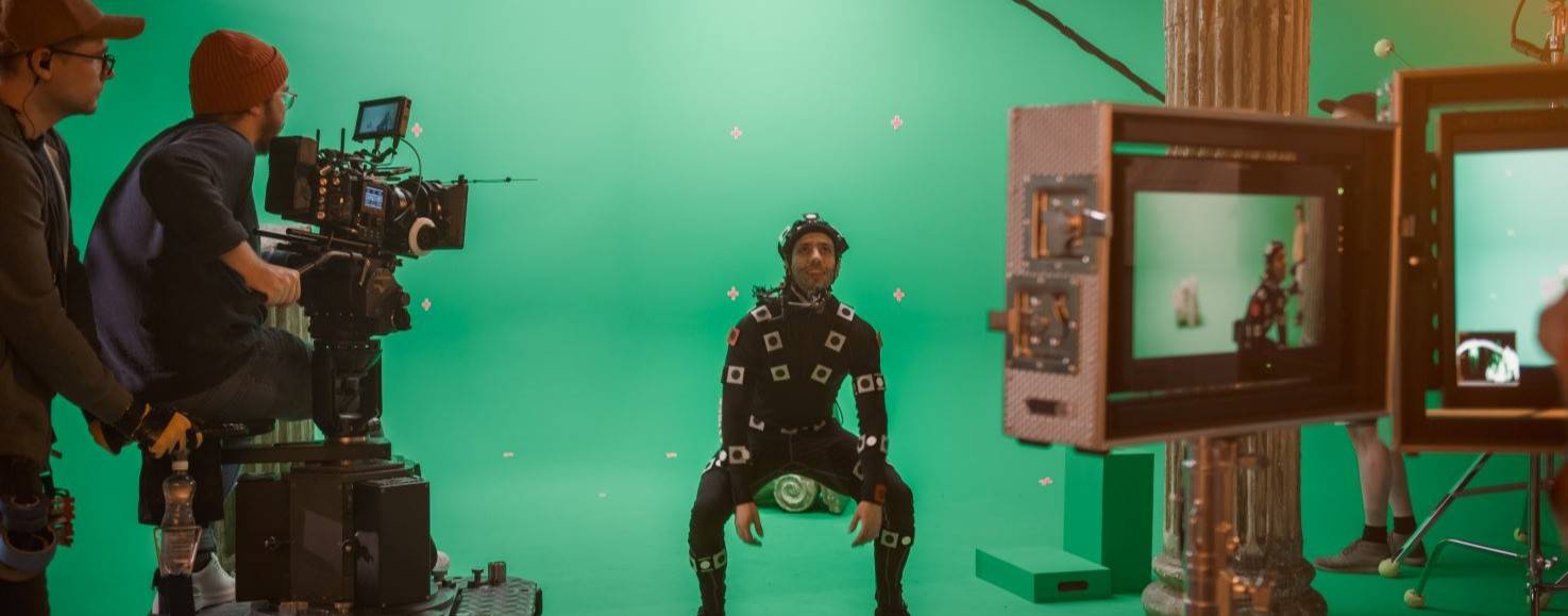 Un actor con traje de captura de movimiento se prepara para una grabación en un estudio con fondo verde.