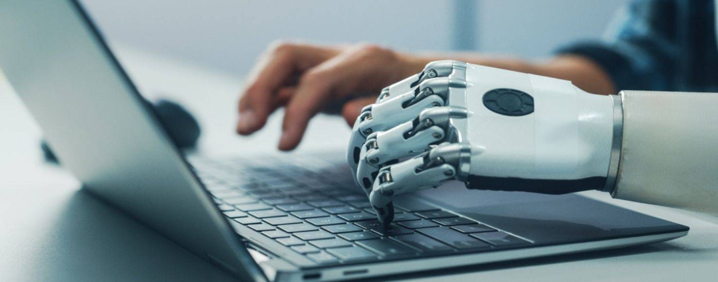 Un brazo robótico está escribiendo en un ordenador portátil.