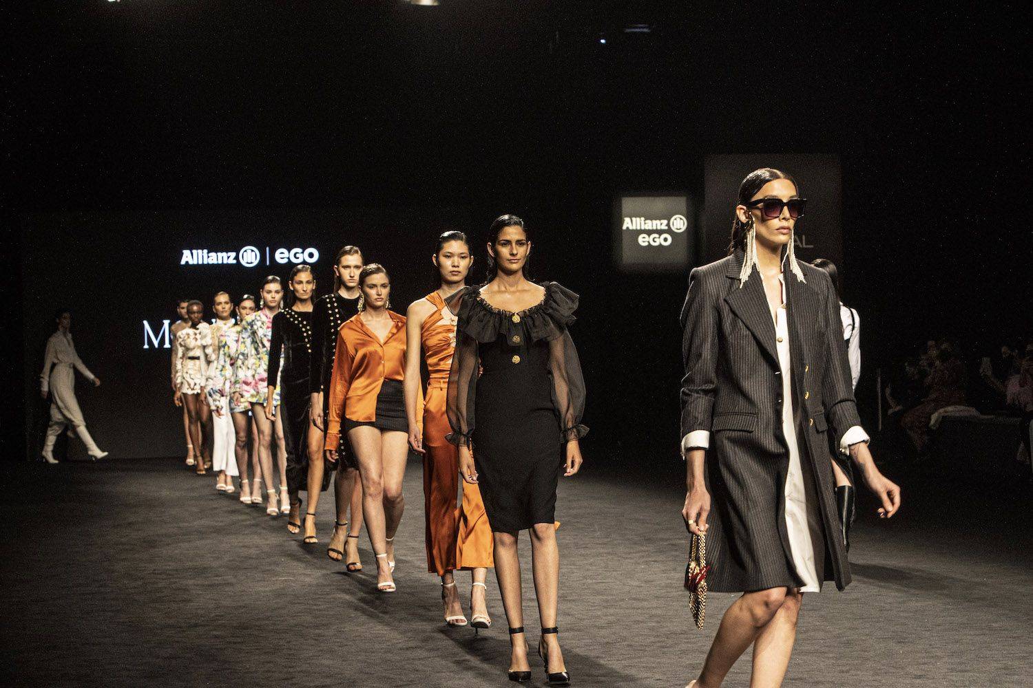 Desfile de moda con varias modelos vistiendo prendas elegantes en una pasarela.