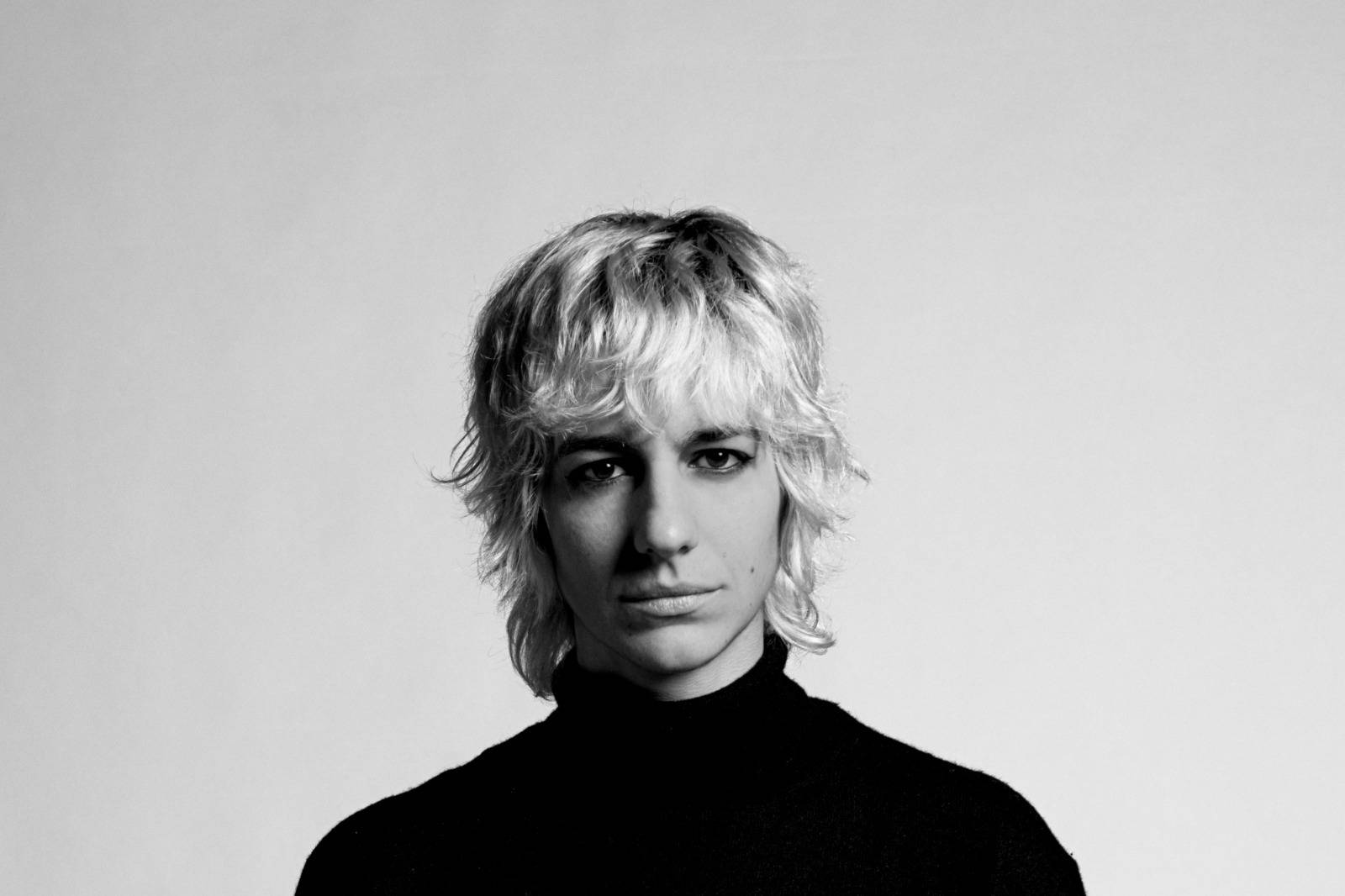 Un retrato en blanco y negro de una persona con cabello rubio y rizado.