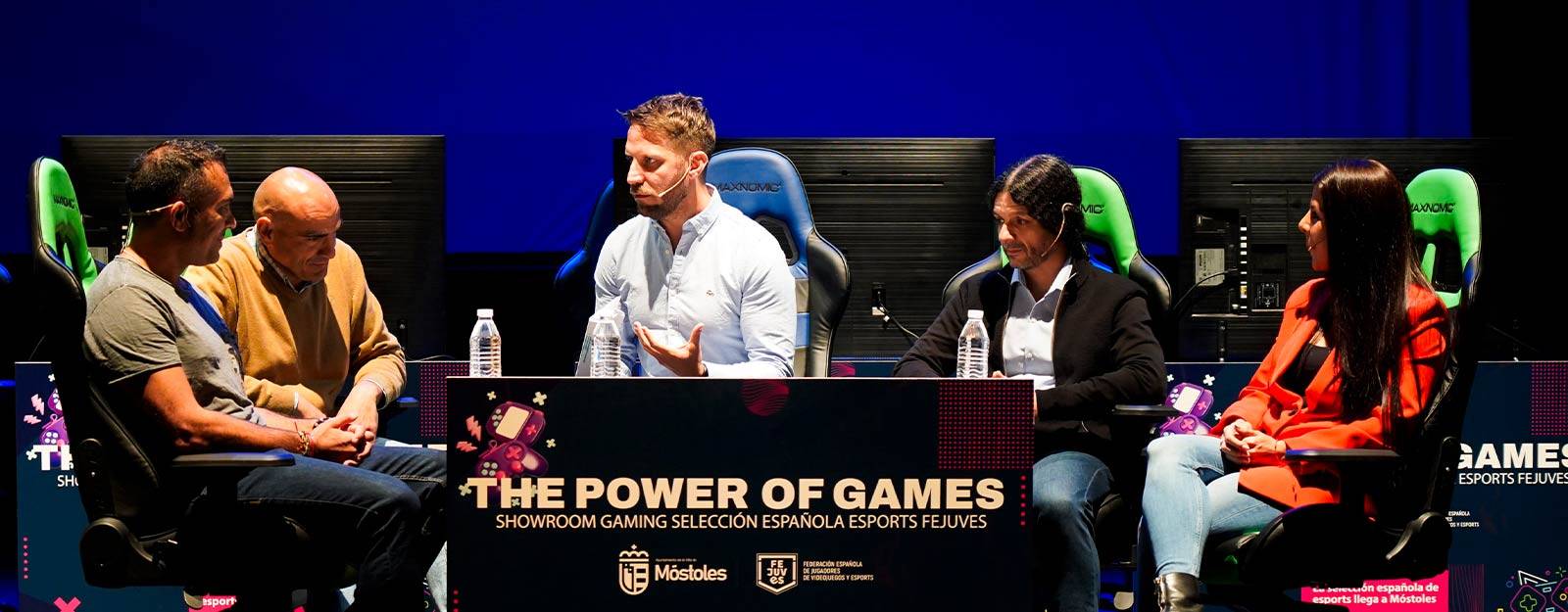 Un panel de discusión sobre videojuegos en un evento de eSports con cuatro ponentes en el escenario.