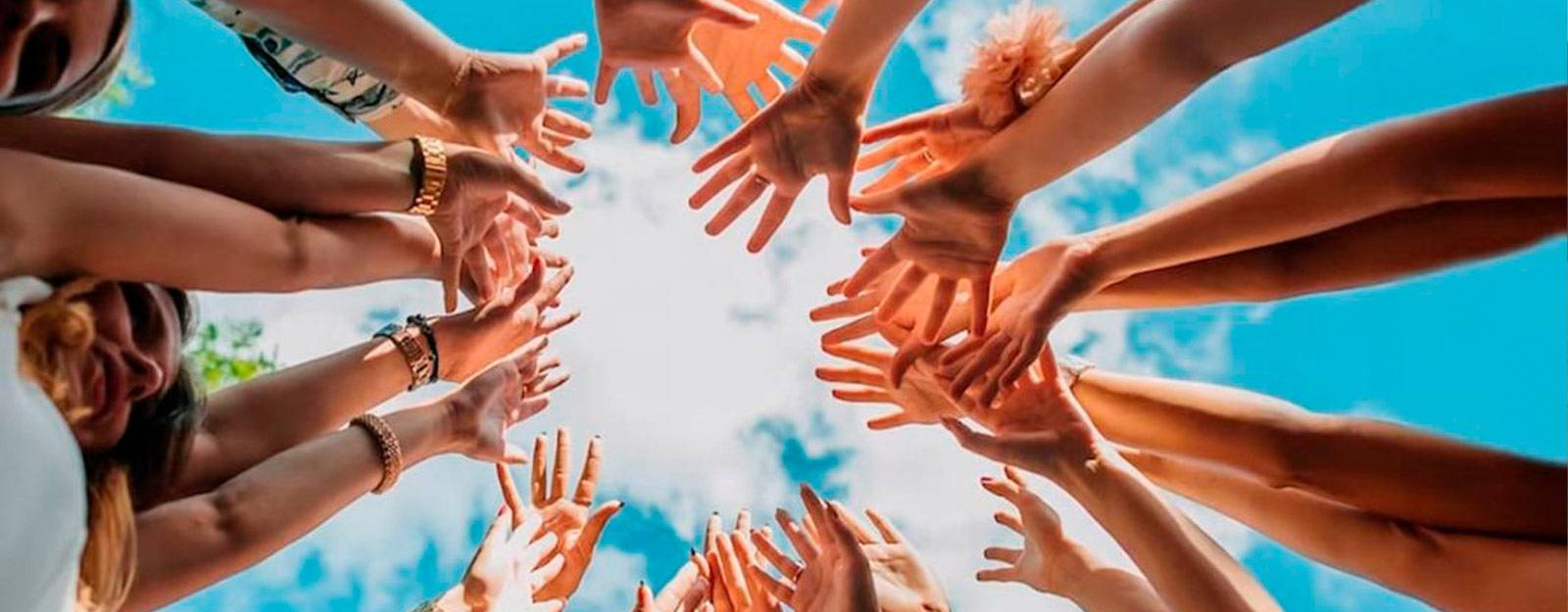 Un grupo de manos alzadas hacia el cielo con un fondo azul.