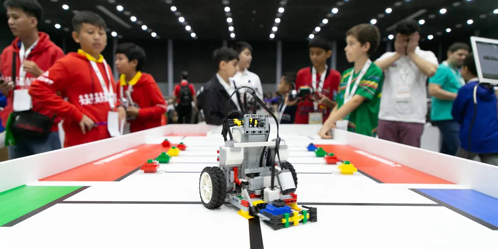 Un grupo de niños observa un robot en una competencia de robótica.